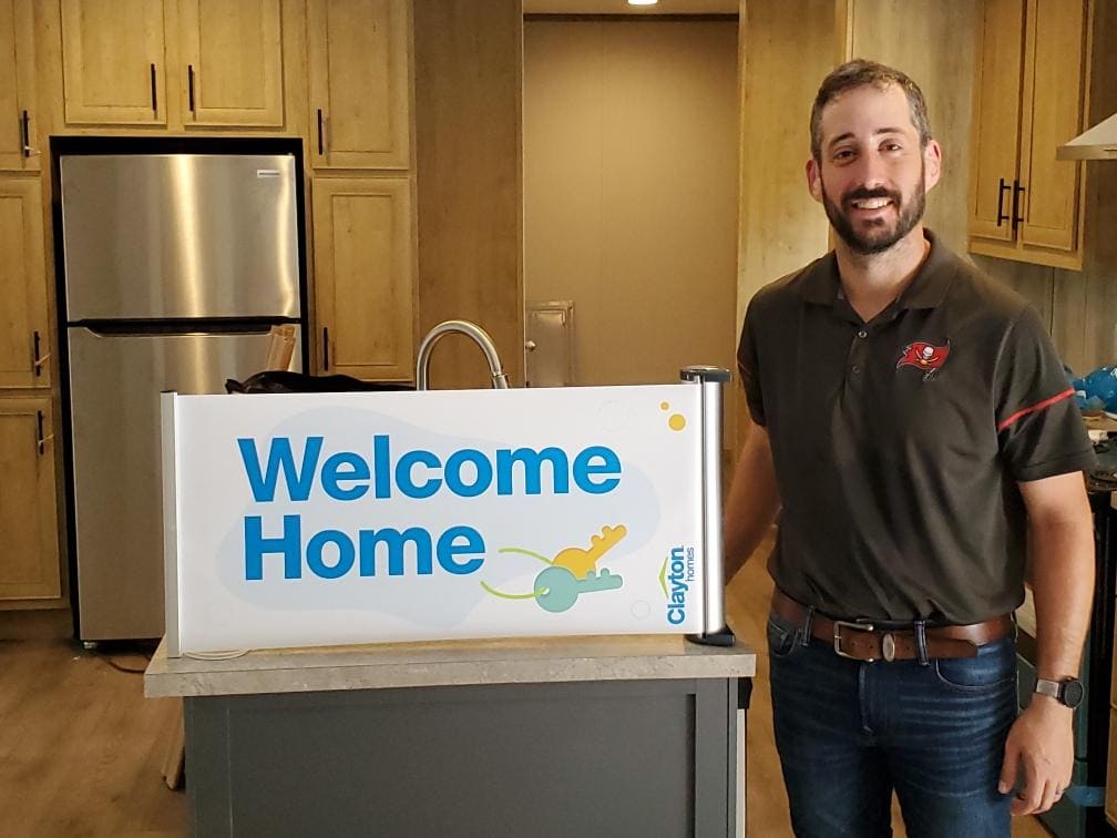 Manufactured Home Retail Person Standing in Kitchen Next to Welcome Home Sign