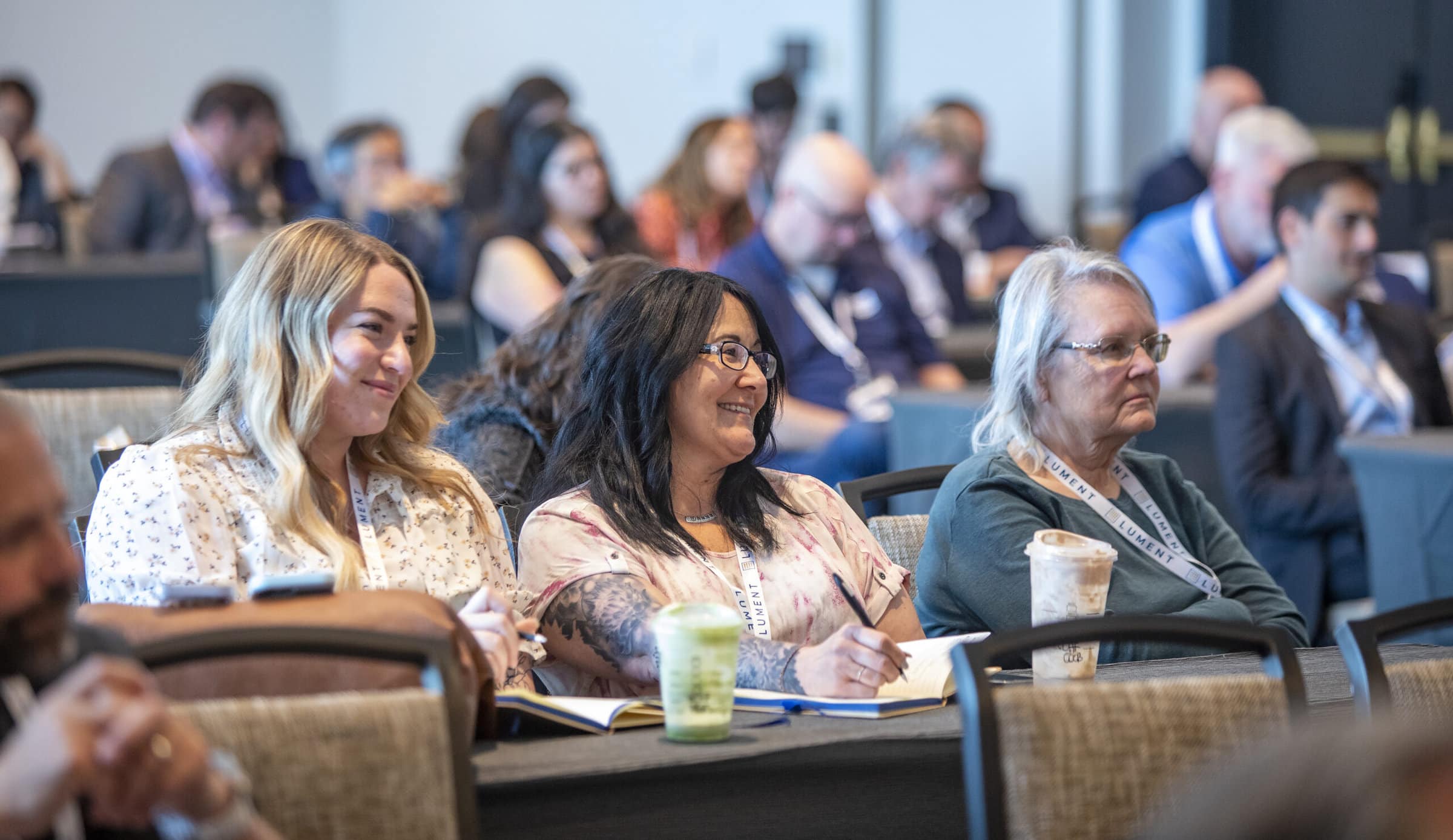 Three women smiling in the audience during event