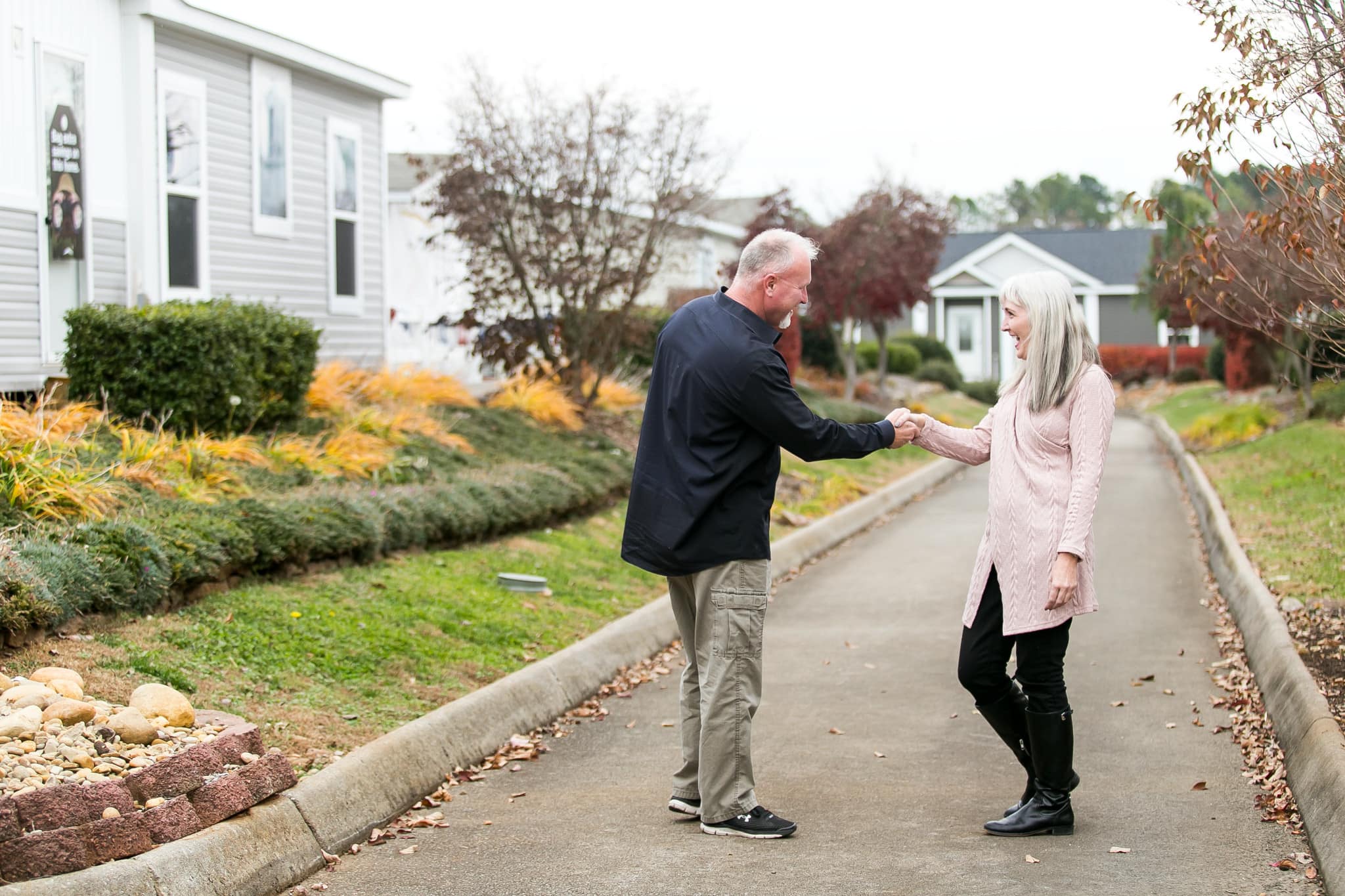 Elderly couple holding hands by manufactured home