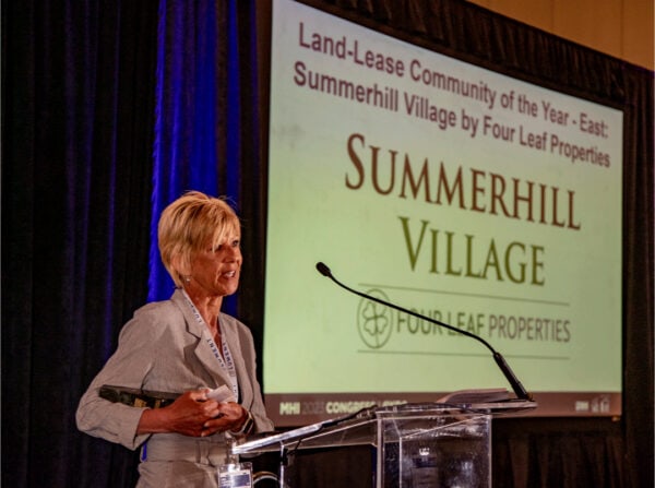 Woman speaking on stage at event, holding an award