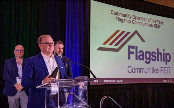 Man on stage speaking at event while holding award