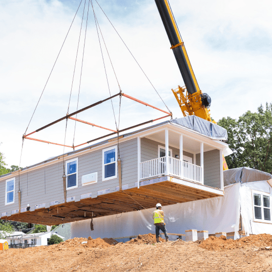 Crane lowering a section of a white home